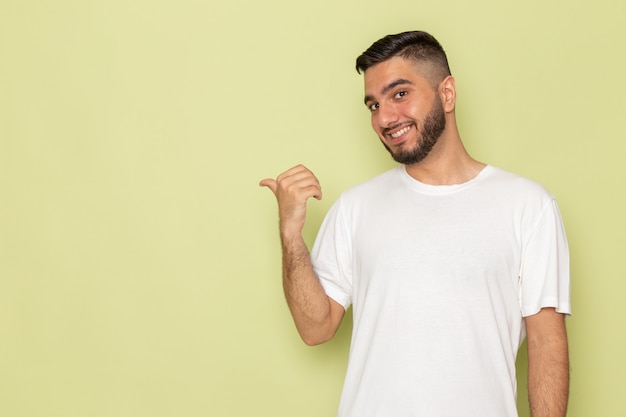 Ein junger Mann der Vorderansicht im weißen T-Shirt, das lächelt und aufwirft