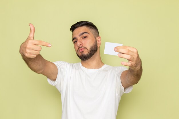 Ein junger Mann der Vorderansicht im weißen T-Shirt, das weiße Karte hält