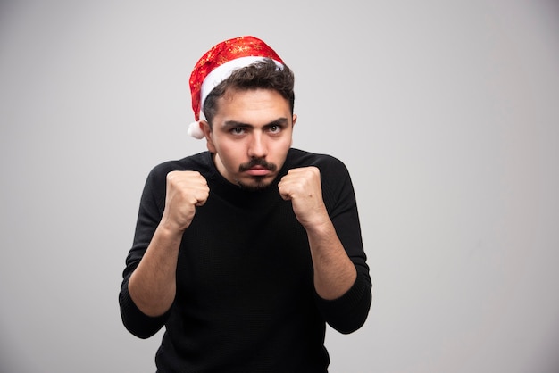 Ein junger Mann im roten Hut des Weihnachtsmanns zeigt seine Fäuste.