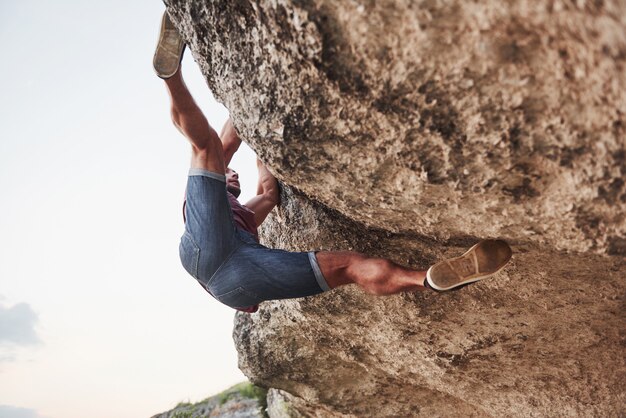 Ein junger Mann klettert auf einen Felsen.