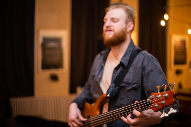 Ein junger mann mit bart spielt eine bassgitarre mit fünf saiten