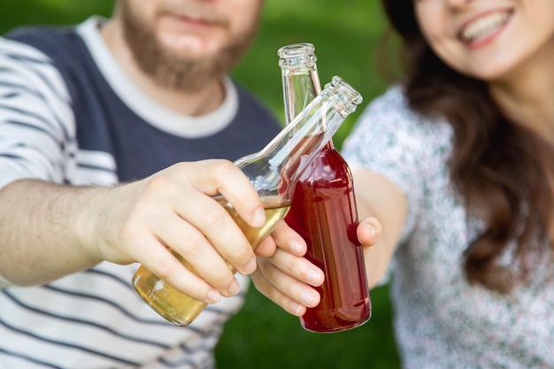 Kostenloses Foto ein junger mann und eine frau trinken bei einem picknick getränke in glasflaschen