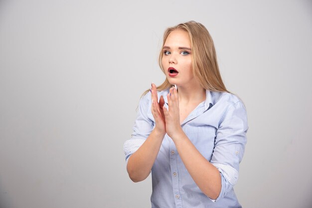 Ein junges Frauenmodell im blauen T-Shirt, das überraschend steht und in die Kamera schaut