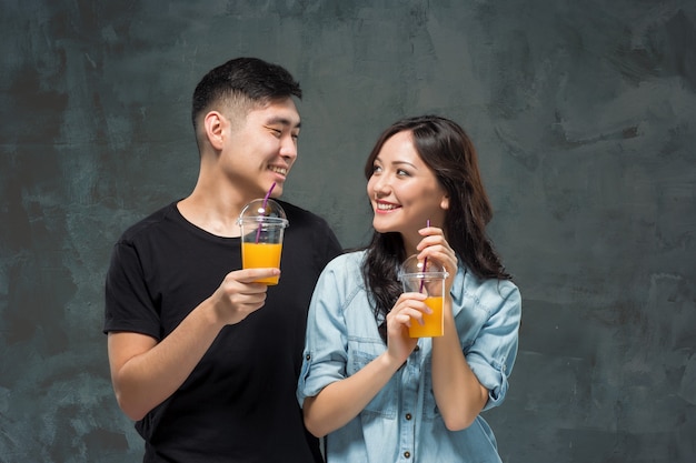 Ein junges hübsches asiatisches paar mit einem glas orangensaft