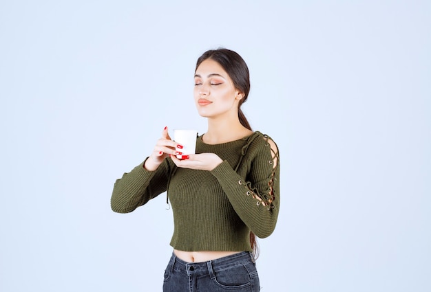 Ein junges hübsches Frauenmodell, das einen Plastikbecher mit heißem Getränk hält.