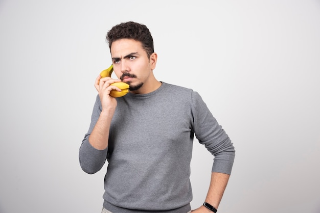 Ein junges Mannmodell, das eine Banane als Telefon hält.