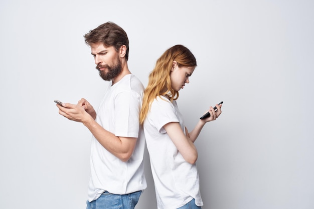 Ein junges paar in weißen t-shirts mit telefonen in den händen isolierter hintergrund