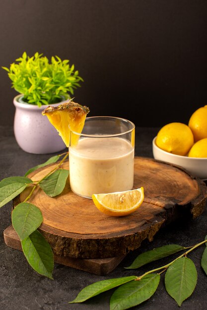 Ein kalter Cocktail der Vorderansicht, der innerhalb des Glases mit grünen Blättern und mit der kleinen Pflanze der Zitronen gefärbt wird, die auf der Dunkelheit isoliert wird
