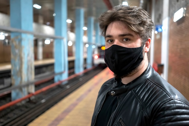 Ein kaukasischer Mann mit Bart in der schwarzen medizinischen Maske, die in der Kamera in der U-Bahn schaut