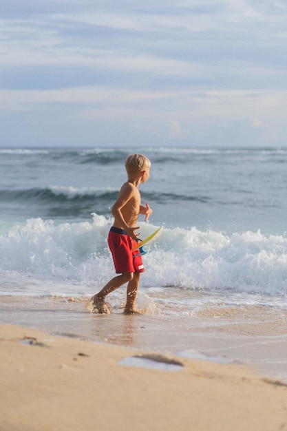 Ein Kind am Strand spielt in den Wellen des Ozeans. Junge auf dem Ozean, glückliche Kindheit. tropisches leben.