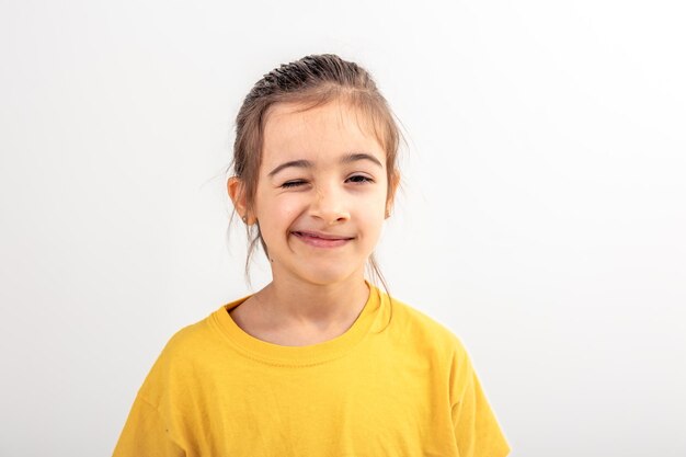 Ein kleines kaukasisches Mädchen macht lustige Gesichter auf einem weißen Hintergrund, isoliert