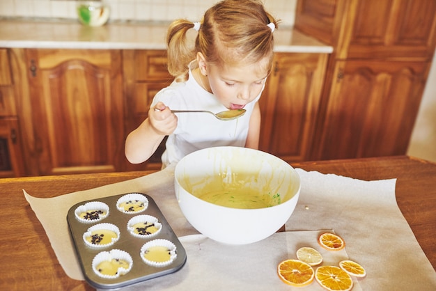 Kostenloses Foto ein kleines mädchen bereitet einen teig für muffins vor.