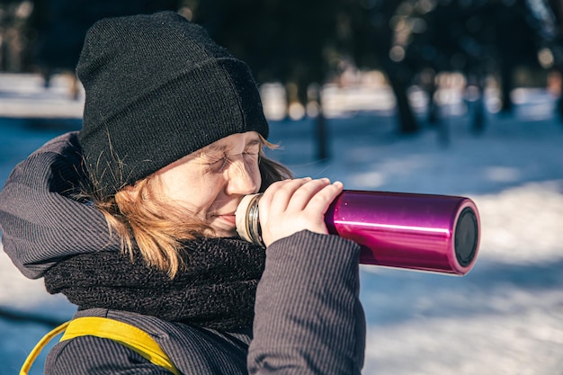 Kostenloses Foto ein kleines mädchen draußen mit thermoskanne an einem kalten wintertag