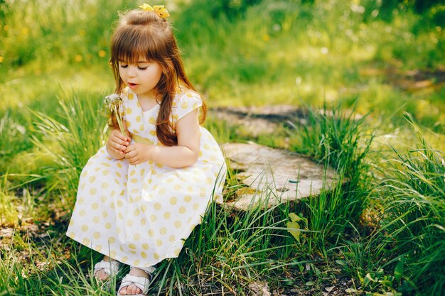 Ein kleines Mädchen mit schönen langen Haaren und in einem gelben Kleid spielt im Sommer