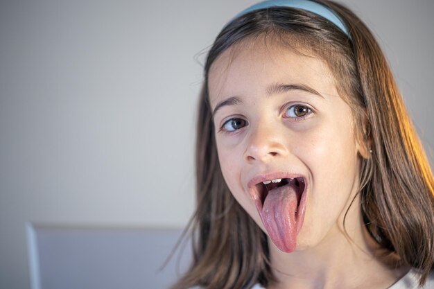 Ein kleines Mädchen öffnet den Mund und zeigt seine Zunge