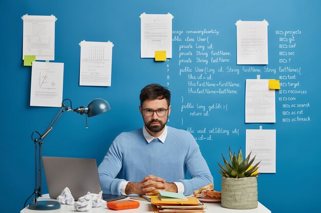 Ein kluger, seriöser Student der IT-Fakultät sitzt an einem modernen Arbeitsplatz