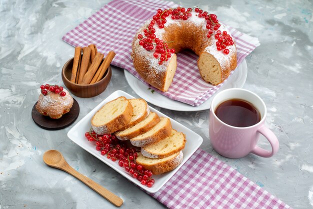 Ein köstlicher Kuchen der Draufsicht mit frischem Zimt der roten Preiselbeeren und Tee auf der weißen Schreibtischkuchen-Keks-Tee-Beere