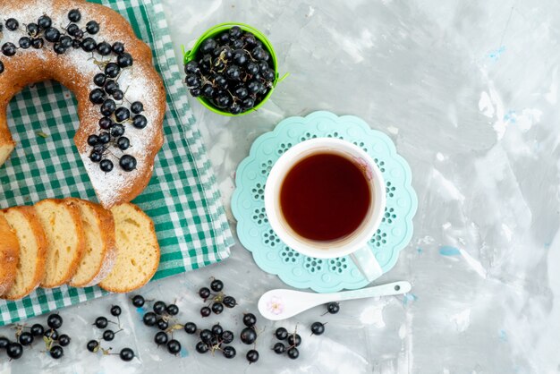 Ein köstlicher Kuchen der Draufsicht mit frischen Blaubeeren und Tee auf der weißen Schreibtischkuchen-Keks-Tee-Beere