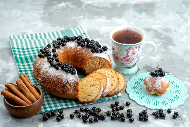 Ein köstlicher Kuchen der Vorderansicht mit frischen Blaubeeren und Tee auf dem weißen Schreibtischkuchen-Keks-Tee-Beeren-Zuckerdessert