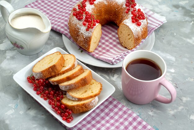 Ein köstlicher Kuchen der Vorderansicht mit frischen roten Preiselbeeren und Tee auf der weißen Schreibtischkuchen-Keks-Tee-Beere