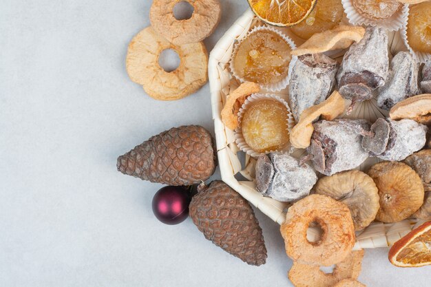 Ein Korb mit gemischten gesunden Trockenfrüchten mit Tannenzapfen. Hochwertiges Foto