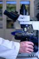 Kostenloses Foto ein laborant, der mit einem modernen mikroskop arbeitet, während er eine forschung durchführt