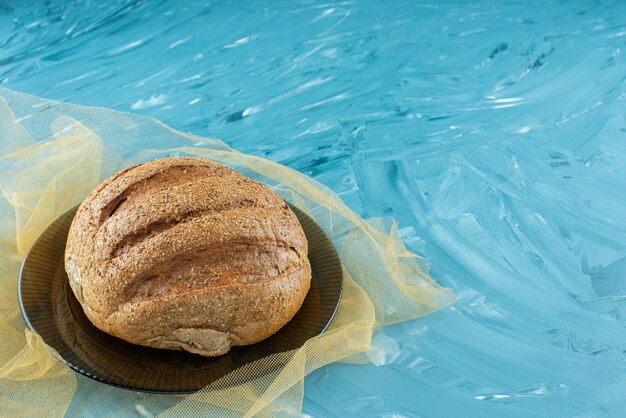 Ein Laib rundes Brot mit einer Kruste auf einer Glasplatte.
