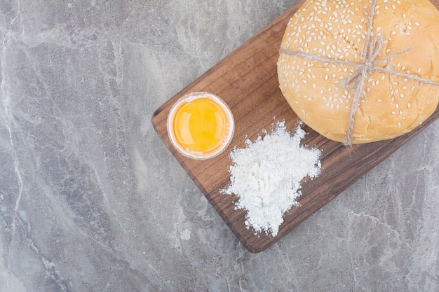 Ein Laib Weißbrot mit Eigelb und Mehl auf Holzbrett