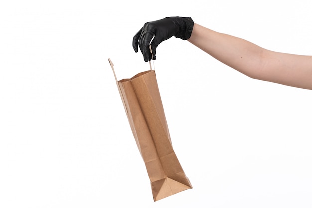 Ein leeres Papierpaket der Vorderansicht, das von Frau in schwarzen Handschuhen auf Weiß gehalten wird