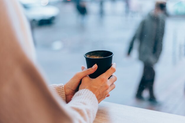 Ein Mädchen in einem gemütlichen Café wärmt sich mit einer Tasse heißen Kaffees auf