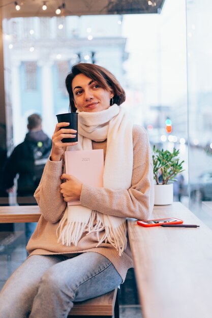 Ein Mädchen in einem gemütlichen Café wärmt sich mit einer Tasse heißen Kaffees auf
