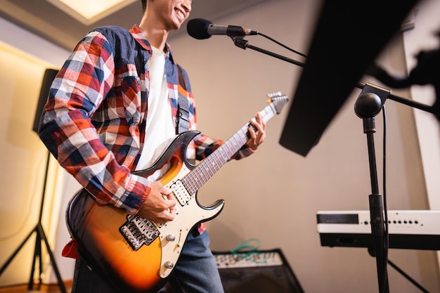 Ein männlicher gitarrist spielt während der proben mit seiner band eine e-gitarre