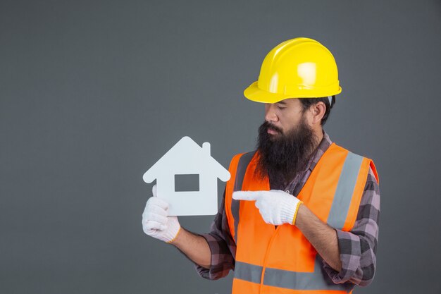 Ein männlicher Ingenieur, der einen gelben Schutzhelm hält ein Symbol des weißen Hauses auf einem Grau trägt.