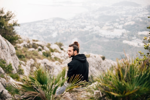 Ein männlicher Wanderer, der auf felsigen Berg sitzt