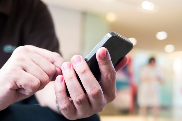 Ein Mann benutzt Telefon über buntem unscharfem bokeh Licht im Büro- und Leutehintergrund