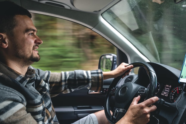 Ein Mann, der ein Auto fährt, fährt in ein bergiges Waldgebiet