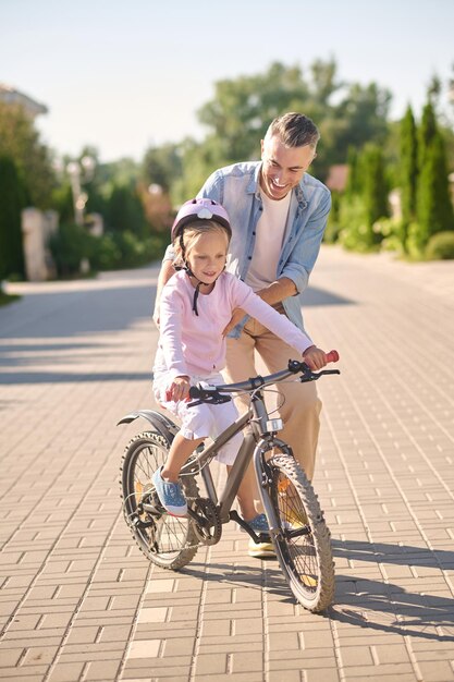 Ein Mann, der ein Mädchen beim Fahrradfahren unterstützt