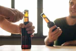 Kostenloses Foto ein mann, der eine person öffnet braune bierflasche im restaurant betrachtet