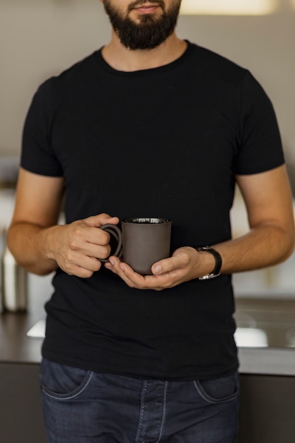 Ein Mann, der eine schwarze Kaffeetasse in seinen Händen hält