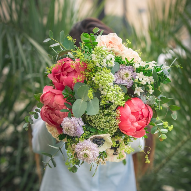 Ein Mann, der einen Blumenstrauß von bunten Sommerblumen anbietet.