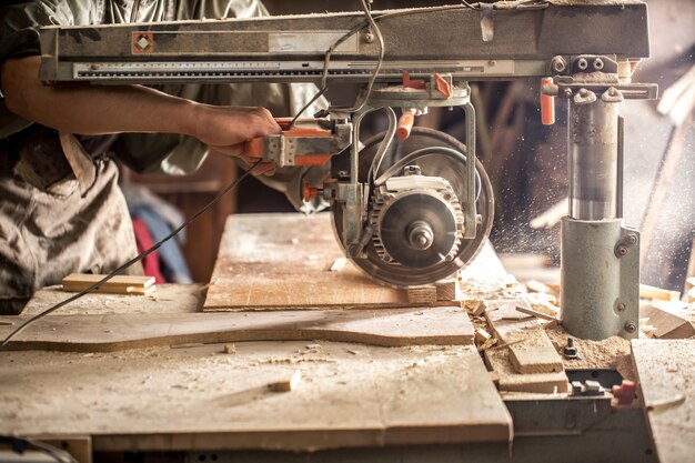 ein Mann, der mit Holzprodukt an der Maschine arbeitet