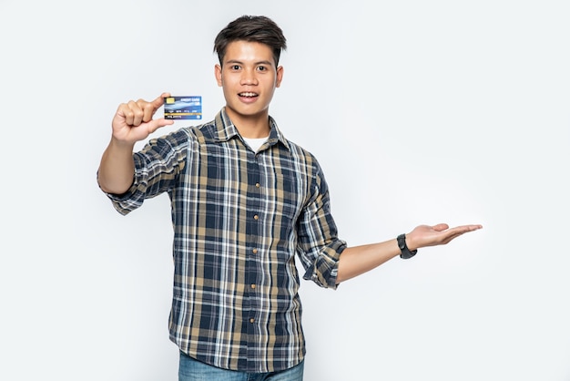 Ein Mann in einem gestreiften Hemd öffnet seine linke Hand und hält eine Kreditkarte
