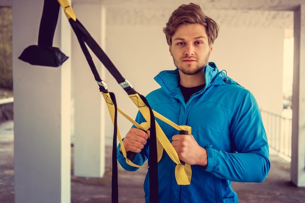 Ein Mann in einem Park, der seine Beinflexibilität mit Fitness-Trx-Streifen verbessert.