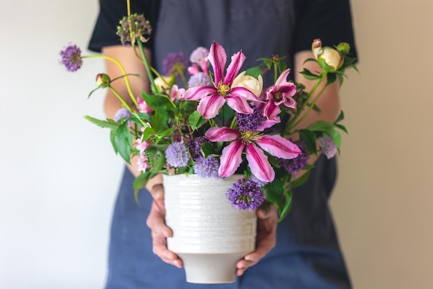 Kostenloses Foto ein mann in einer schürze hält eine vase mit blumen in der nähe