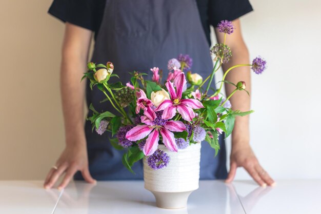 Ein Mann in einer Schürze hält eine Vase mit Blumen in der Nähe