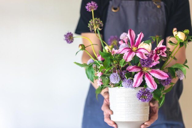 Kostenloses Foto ein mann in einer schürze hält eine vase mit blumen in der nähe