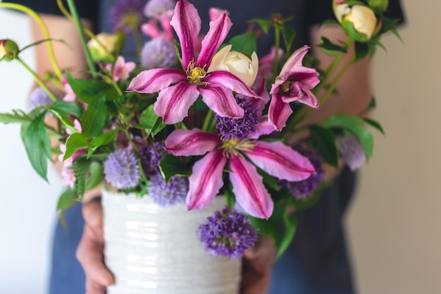 Kostenloses Foto ein mann in einer schürze hält eine vase mit blumen in der nähe