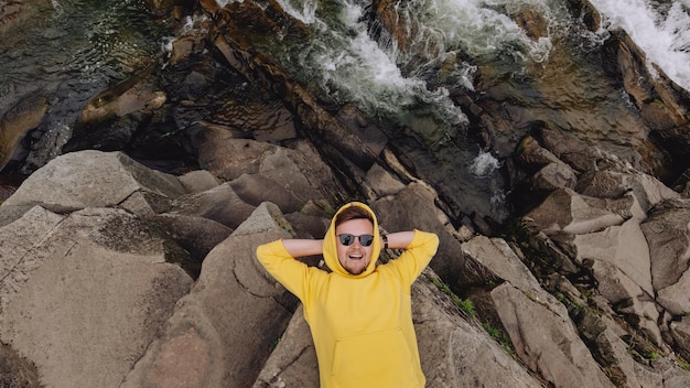 Ein mann in gelber jacke liegt auf einer klippe an einem bergfluss draufsicht mit platz für text