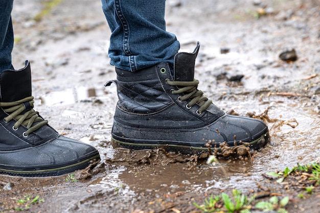 Ein Mann in Jeans und Stiefeln geht bei Regenwetter durch den Sumpf