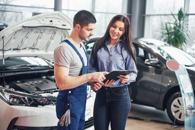 Ein Mann Mechaniker und Frau Kunde diskutieren Reparaturen an ihrem Fahrzeug durchgeführt